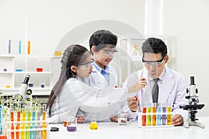 Young Asian boy and girl smile and having fun while learning science experiment in laboratory with teacher in classroom. Study