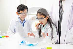 Young Asian boy and girl student wearing protective google while study and do science experiment in classroom with teacher.