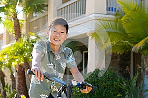 Young Asian boy on his bike in front of the house