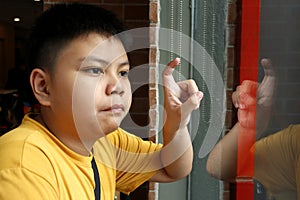 Young Asian boy looking out a glass window and