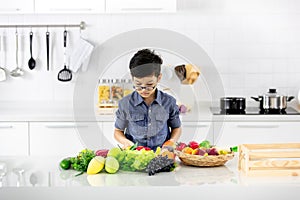 Young Asian boy looking to pile of fake fruits and vegetables in