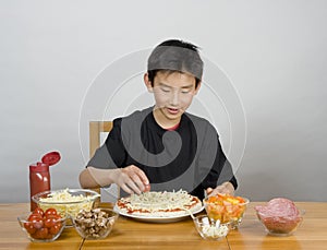 Young Asian boy making pizza