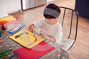 Young Asian Boy Painting Picture And Having Fun Doing Craft On Table At Home