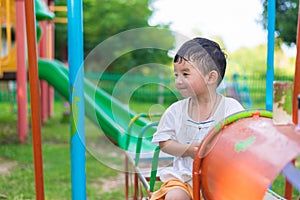 Young Asian boy play a iron train swinging at the playground under the sunlight in summer.