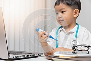 Young asian boy playing doctor and holding a thermometer