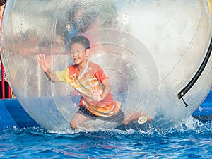 Young Asian boy playing inside a floating water walking ball