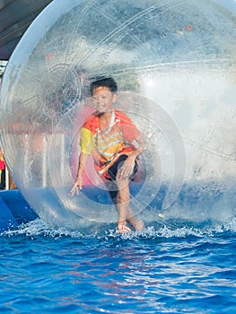 Young Asian boy playing inside a floating water walking ball
