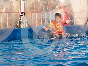 Young Asian boy playing inside a floating water walking ball