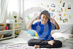 Young asian boy is smiling and listening to music on bedroom