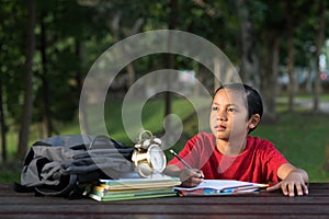 Young asian boy studying at park while looking at empty space