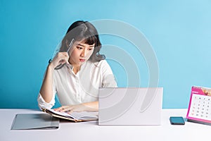 Young asian buisness woman working on blue background