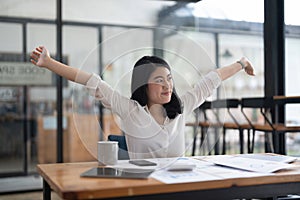 Young Asian Business Accountant woman stretching herself and relax while working hard.