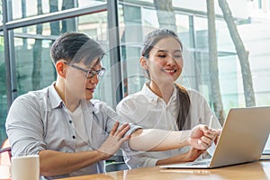 Young Asian business couple  using laptop computer working together in coffee shop. college student discussing to project planning