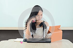 young asian business executive working in office calling customers and compared data in tablet