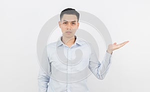 Young asian business man with blue shirt pointing to the side with a hand to present a product or an idea isolated on white