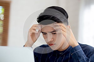 Young asian business man headache during working on laptop computer with deadline on desk at home.