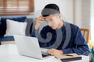 Young asian business man headache during working on laptop computer with deadline on desk at home.