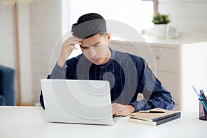 Young asian business man headache during working on laptop computer with deadline on desk at home.