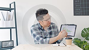 Young Asian business man leading remote video call conference meeting, look at camera, use digital tablet in home office