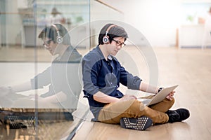 Young Asian business man listening to music while using laptop