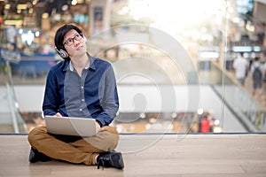 Young Asian business man listening to music while using laptop