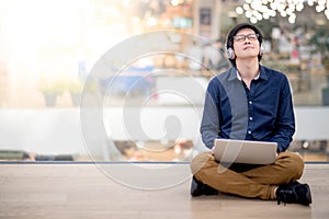 Young Asian business man listening to music while using laptop