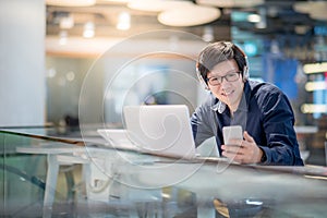 Young Asian business man listening to music while working with l