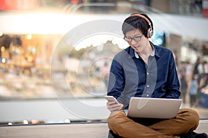 Young Asian business man listening to music while working with l