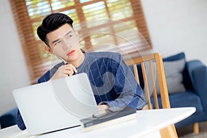 Young asian business man planning working and using laptop computer on desk at home.
