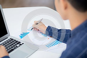 Young asian business man pointing document data graph and chart with pen, marketing and investment.