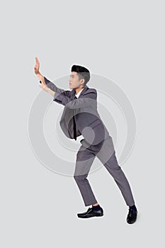 Young asian business man pushing something  on white background, businessman strong and with expression difficult.