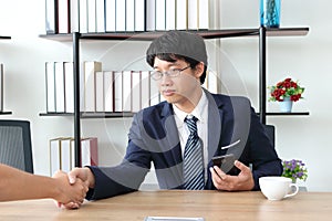 Young Asian business man shaking hands with partners after finishing a meeting. Handshake greeting deal concept