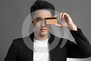 Young asian business man showing credit card isolated over gray background