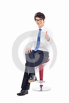 Young Asian business man sitting on the chair and showing thumb