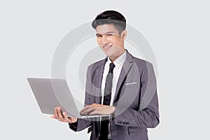 Young asian business man standing work on laptop computer to internet online isolated on white background.