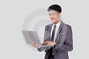 Young asian business man standing work on laptop computer to internet online isolated on white background.