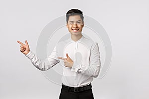 Young asian business man in a suit pointing with his finger on the white background.