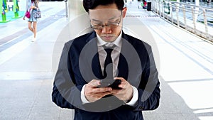 Young Asian business man in suit using mobile smart phone at street in city.