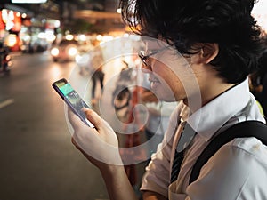 Young Asian business man using mobile smart phone in the street at night. Social and internet of thing concept