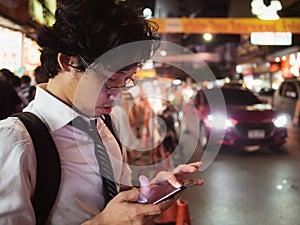 Young Asian business man using mobile smart phone in the street at night. Social and internet of thing concept