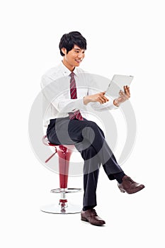 Young Asian business man using a pad PC sitting on the chair.