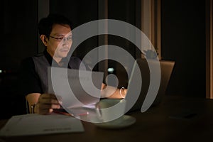 young Asian business man working on laptop in night at office