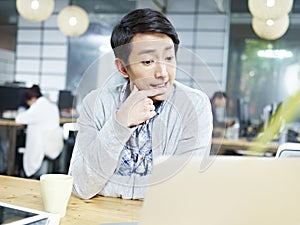 Young asian business person thinking hard in office