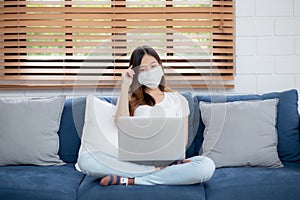 Young asian business woman in face mask think idea and work from home on laptop computer online to internet.