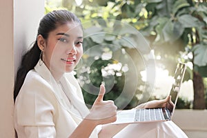 Young Asian business woman with laptop show thumb up hand. Internet of things concept.