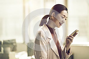 Young asian business woman looking at cellphone