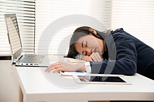 Young Asian business woman lying down on the desk in office because tired overworked.