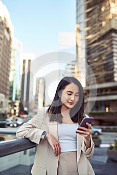 Young Asian business woman professional standing in city using phone.