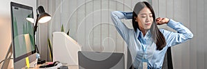Young Asian Business woman sitting on the chair stretching herself and exercise for relaxation while working hard at office