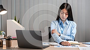 Young Asian Business woman sitting on the chair stretching herself and exercise for relaxation while working hard at office